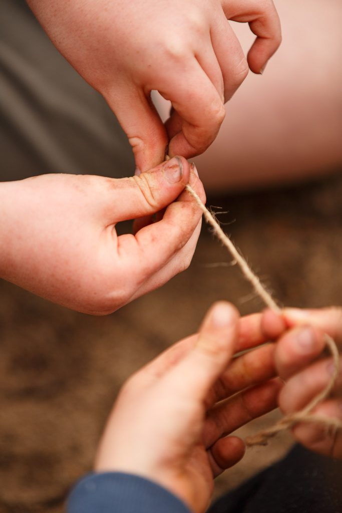Hands unwinding jute string