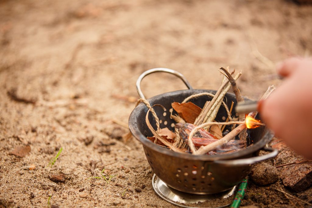 A small colander full of kindling, about to be set alight by a fire steel