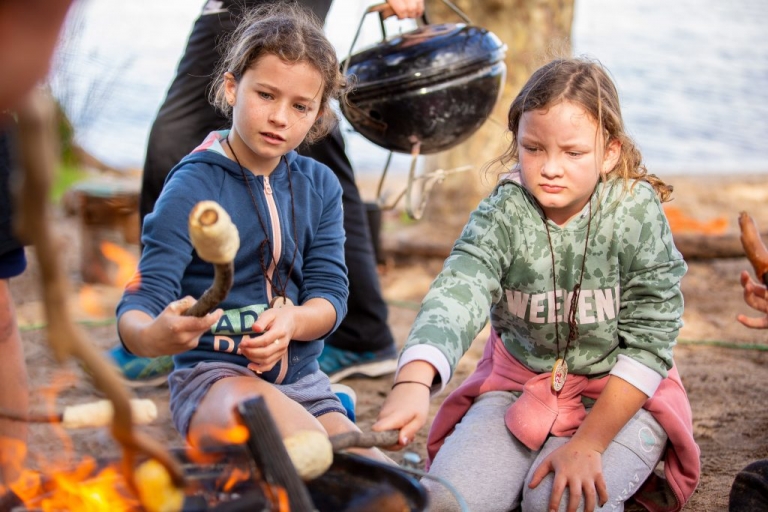 Two children cooking damper over a fire